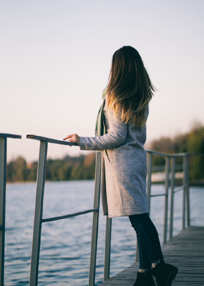 A woman is standing on a pier overlooking a body of water.