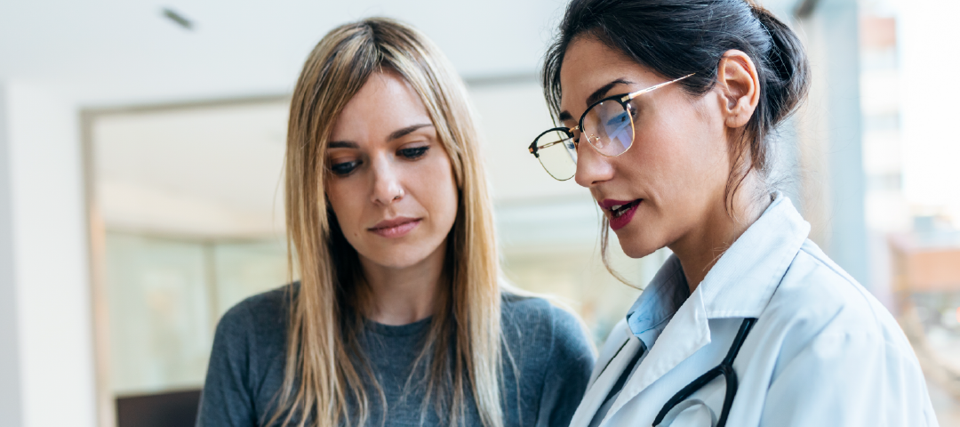 A doctor and a patient are looking at a tablet together.