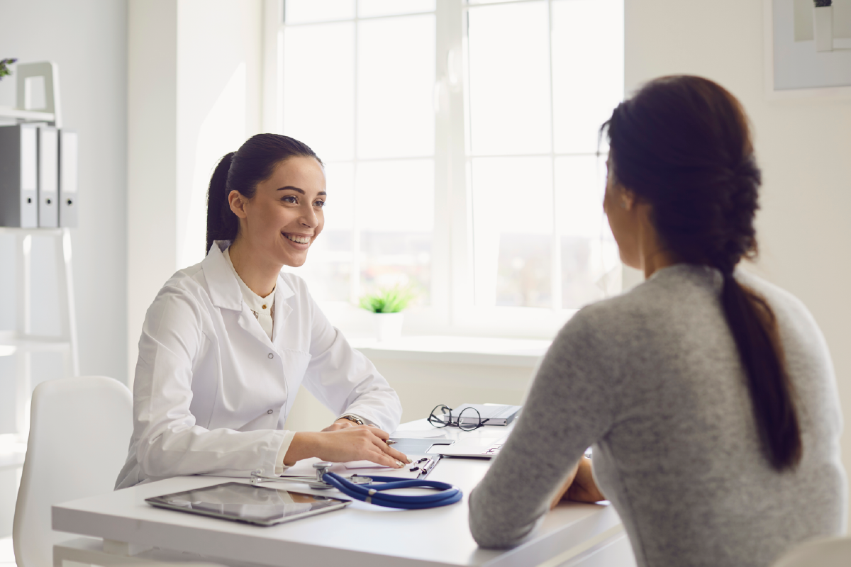 A woman is sitting at a table talking to a doctor.