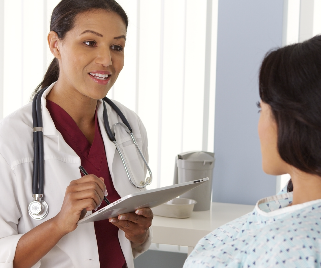 A doctor is talking to a patient who is wearing a hospital gown