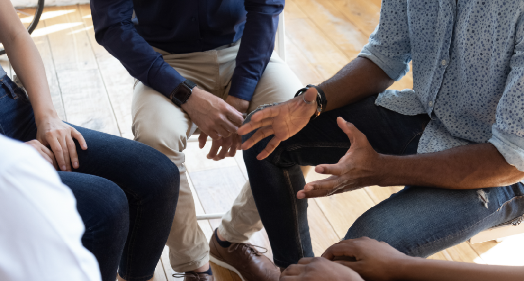 A group of people are sitting in a circle talking to each other.