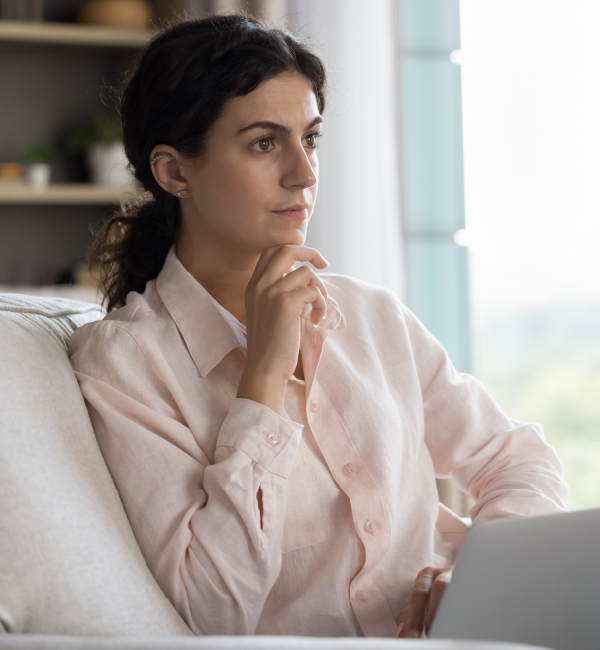 A woman is sitting on a couch using a laptop computer.