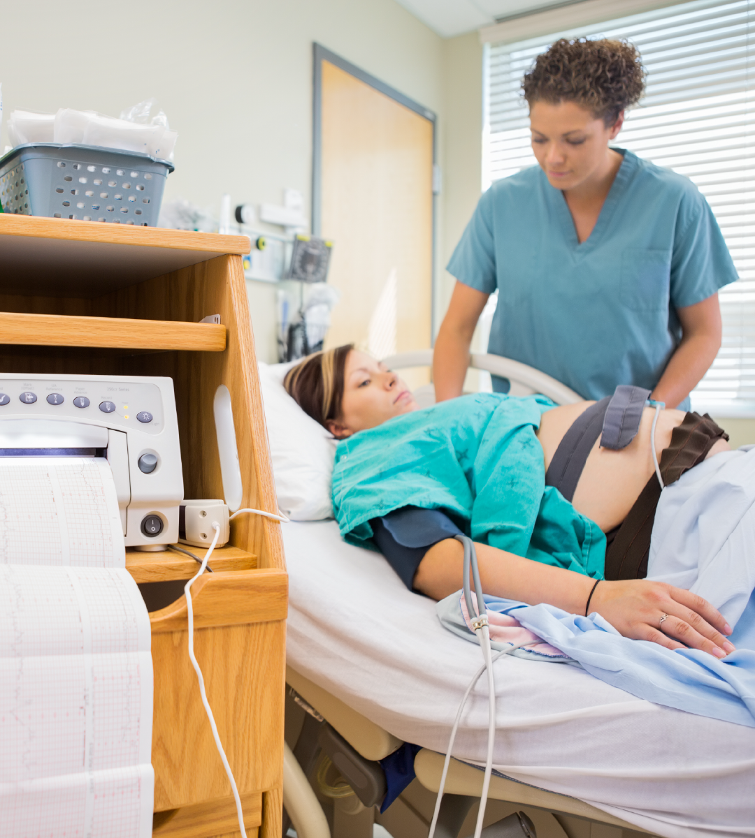 A woman in a hospital bed is being examined by a nurse