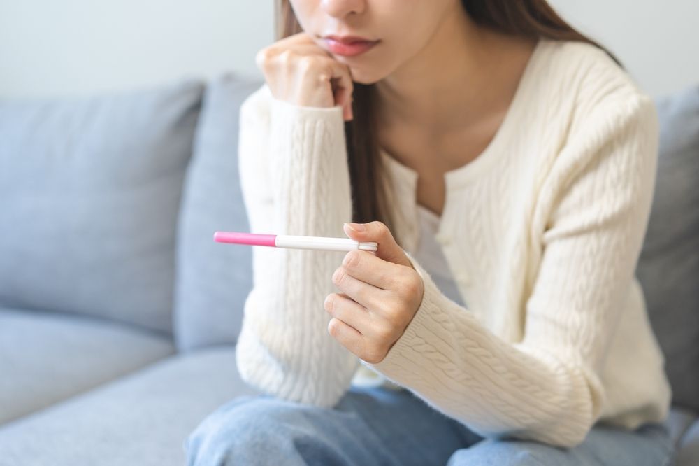 A young woman looking at a pregnancy test.