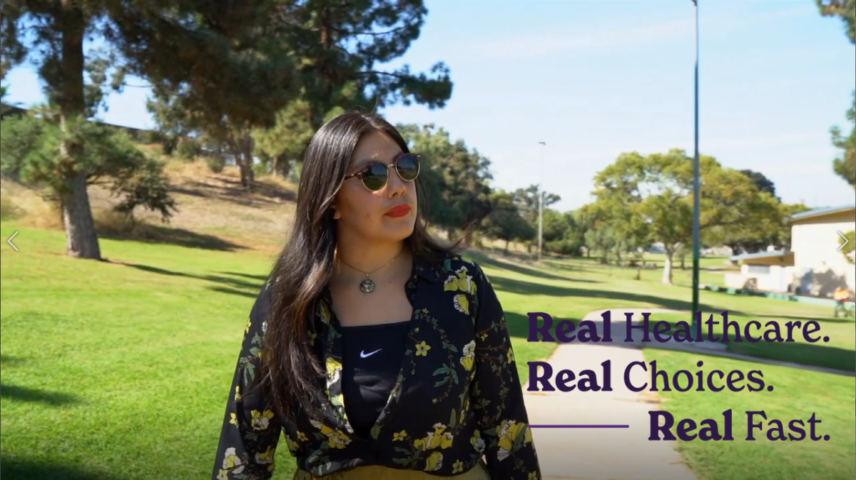 A woman wearing sunglasses is standing in a park.