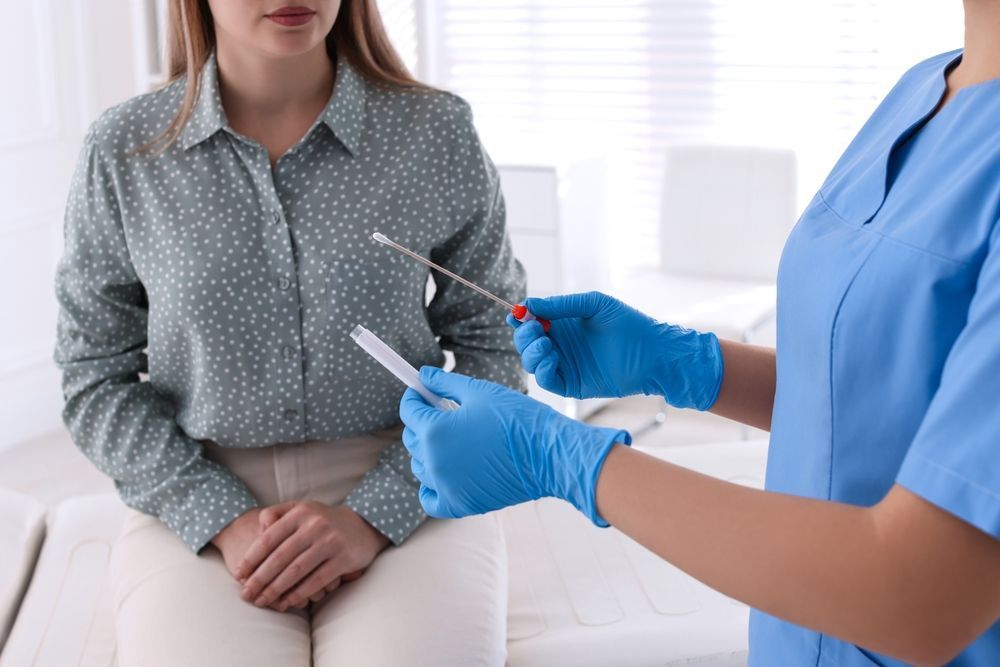 A nurse is holding a swab in front of a patient.