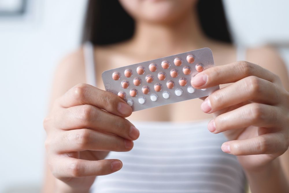 A woman is holding a blister pack of contraceptive pills in her hands.