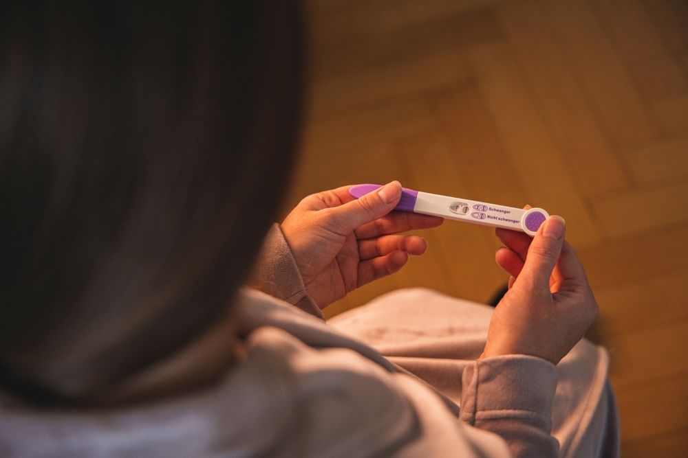 A woman is holding a pregnancy test in her hands.