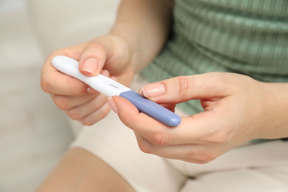 Woman holding a pregnancy test, with the result display facing up.