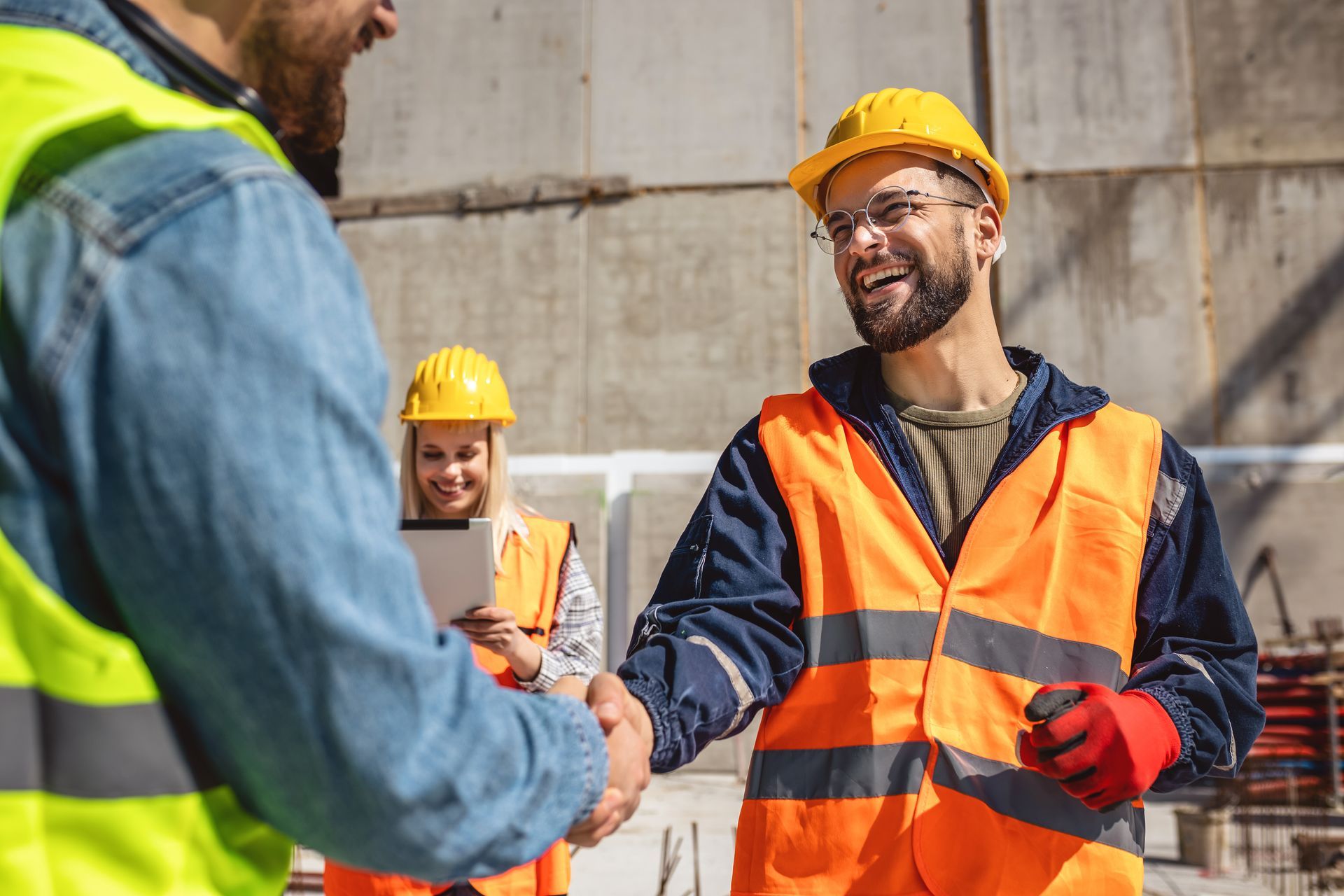 A group of construction workers are shaking hands on a construction site.
