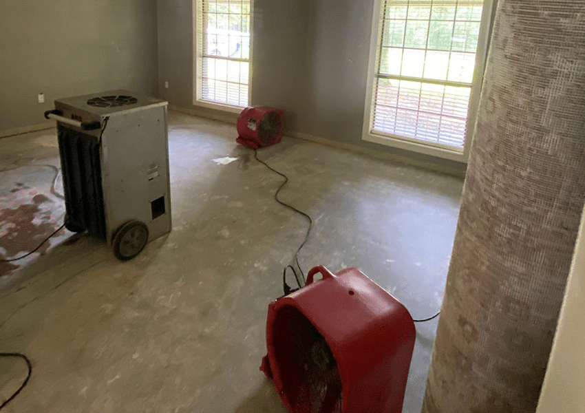 Room with drying equipment after water damage, including a large dehumidifier and air movers.
