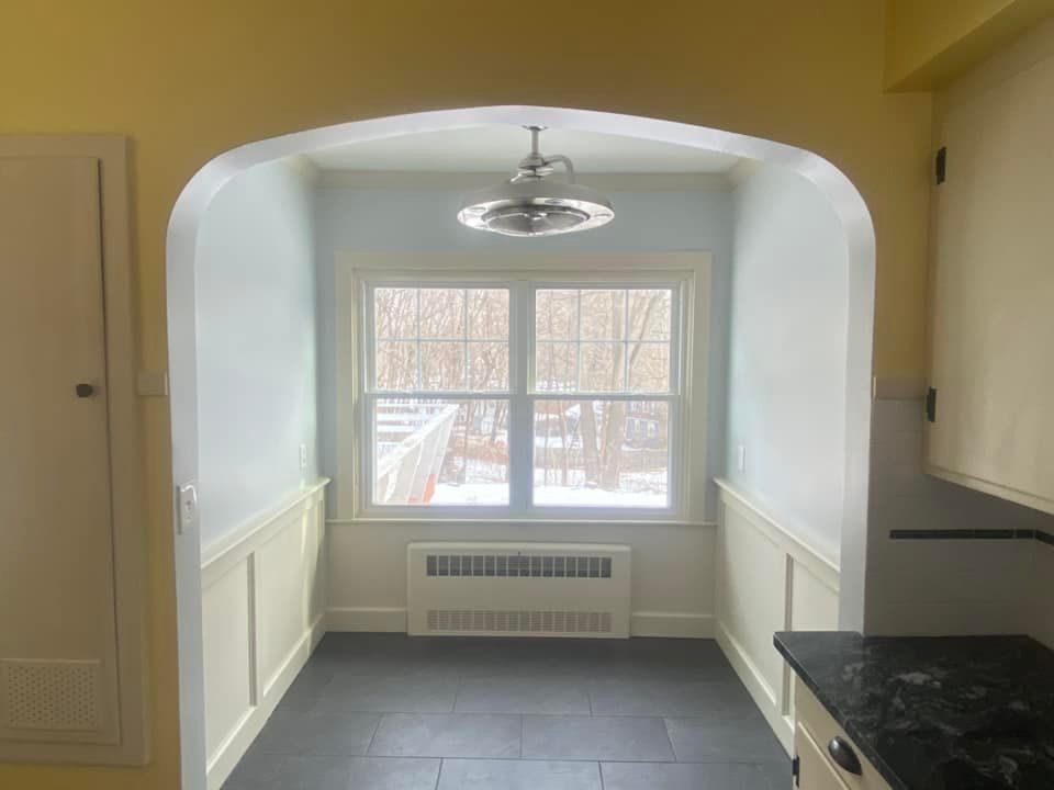 An empty kitchen with a ceiling fan and a window