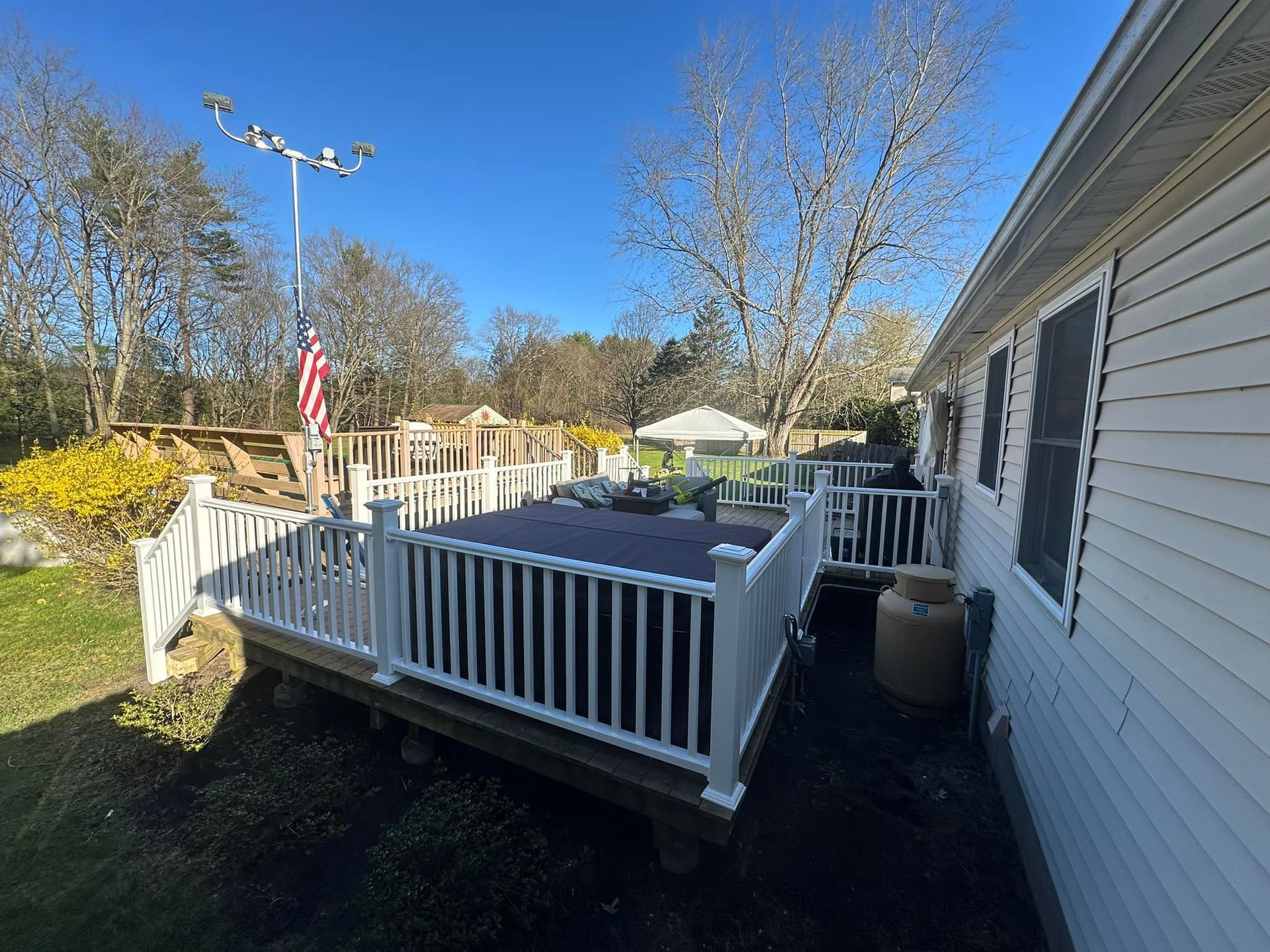 A white house with a large deck in front of it.