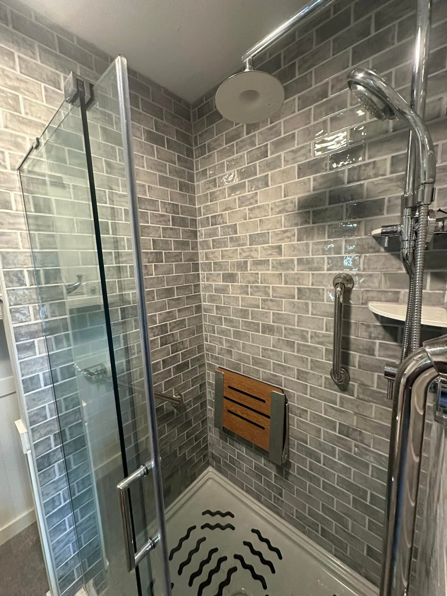 A bathroom with a walk in shower with a wooden seat.