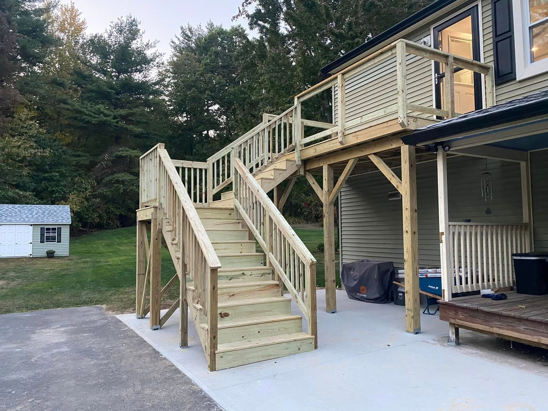 A wooden deck with stairs leading up to it is in front of a house.