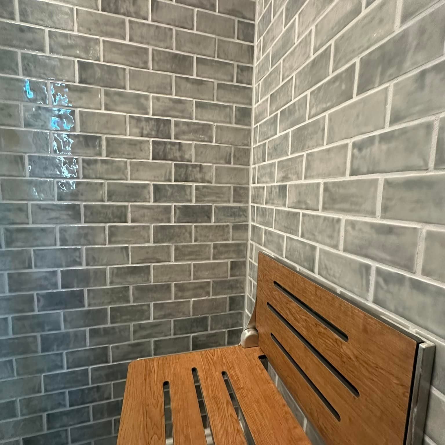There is a wooden bench in the corner of the shower.
