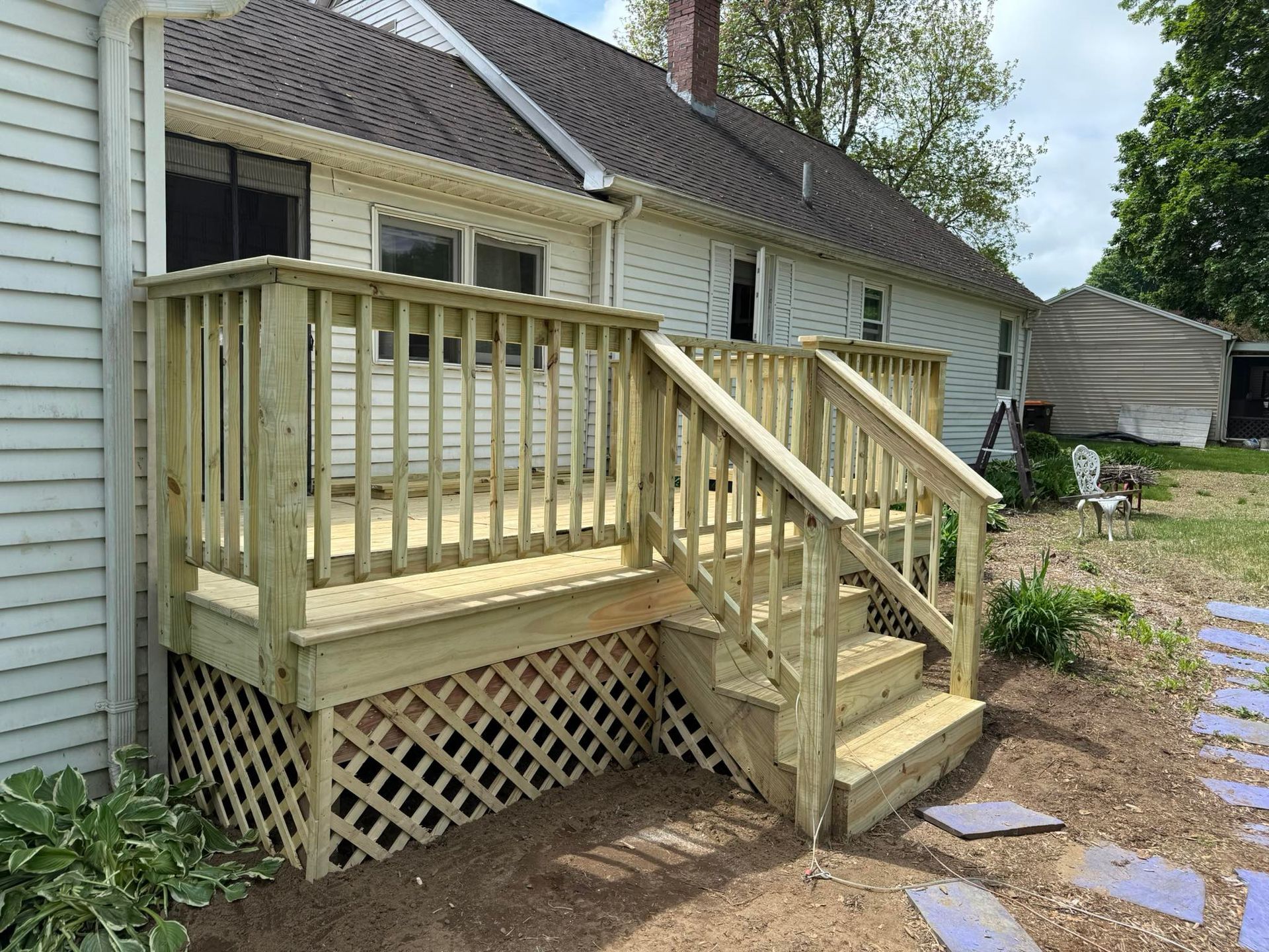 A wooden deck with stairs is in front of a house.