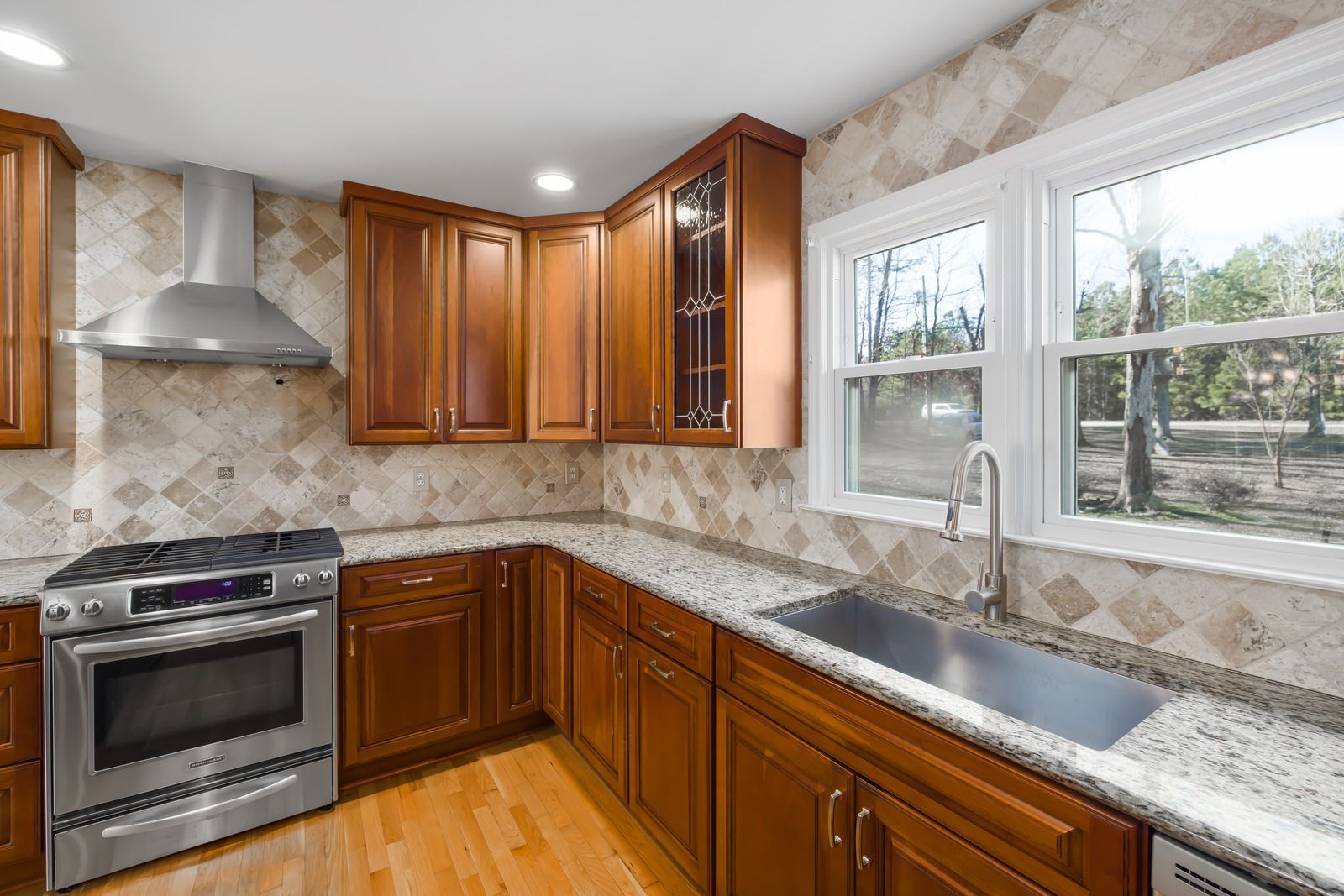 A kitchen with wooden cabinets , stainless steel appliances , granite counter tops , and a sink.