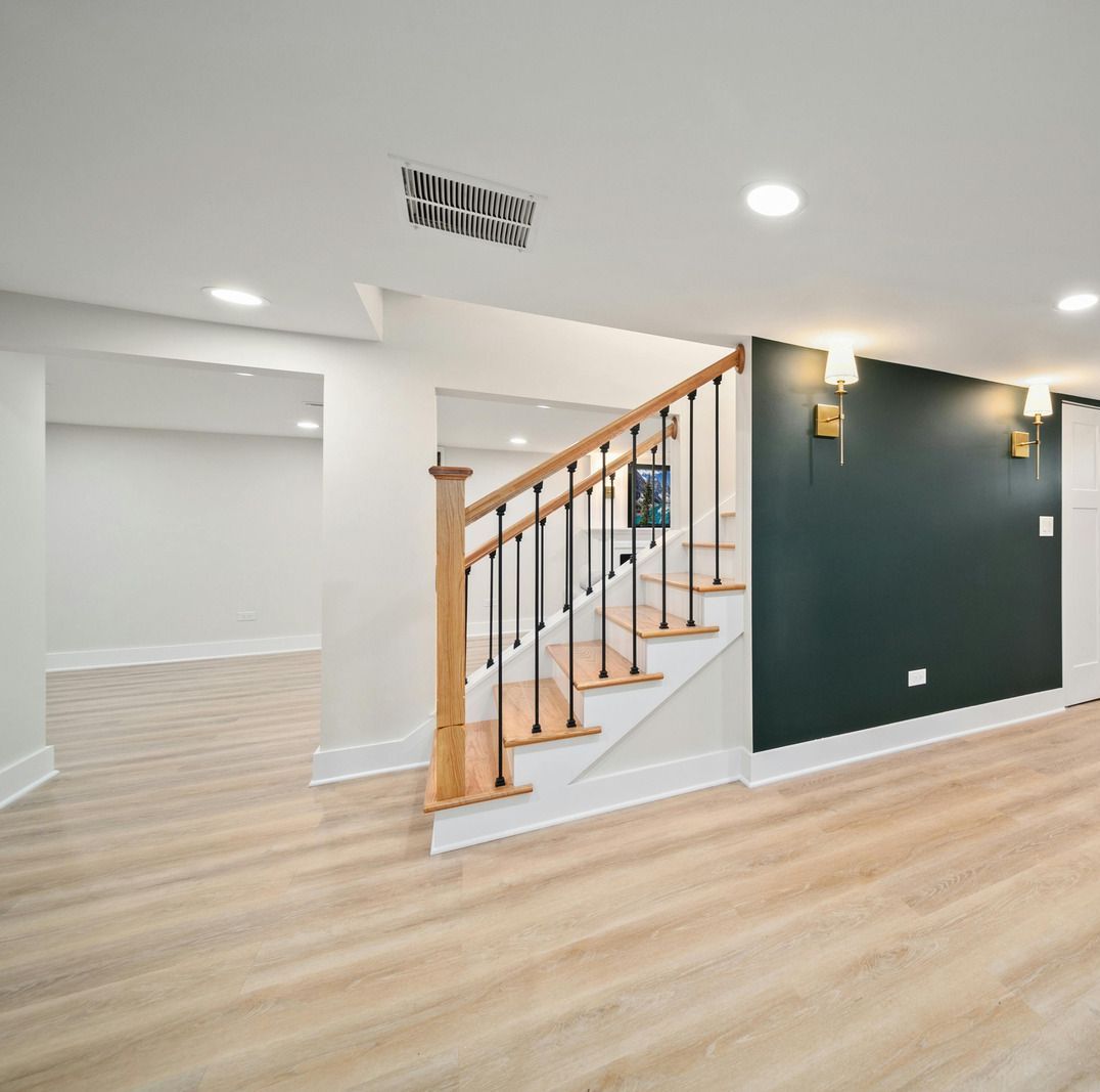 An empty basement with wooden floors and stairs.
