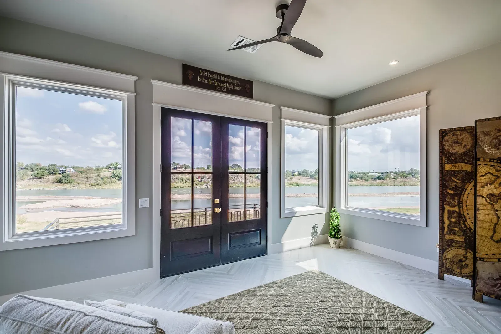 A living room with a lot of windows and a ceiling fan.