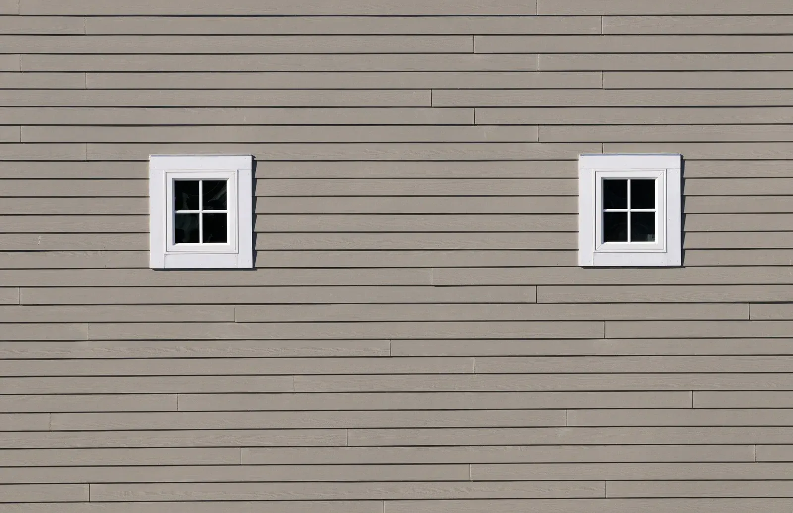 There are two windows on the side of a house.