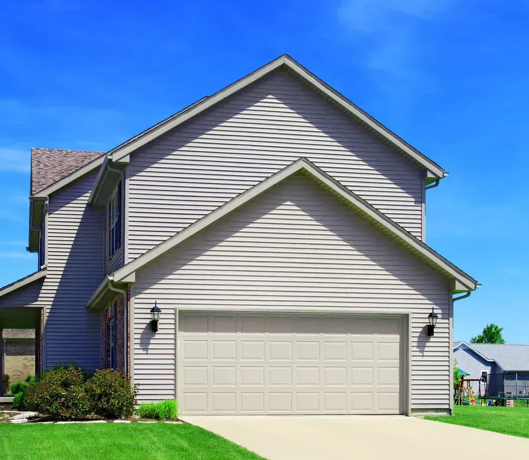 A house with a large garage door and a blue sky in the background.