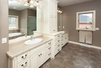 A bathroom with two sinks , two mirrors , and a window.