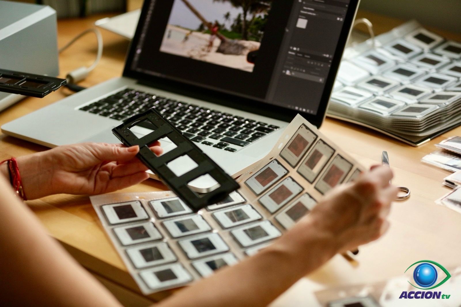 Una persona sostiene una diapositiva frente a una computadora portátil.