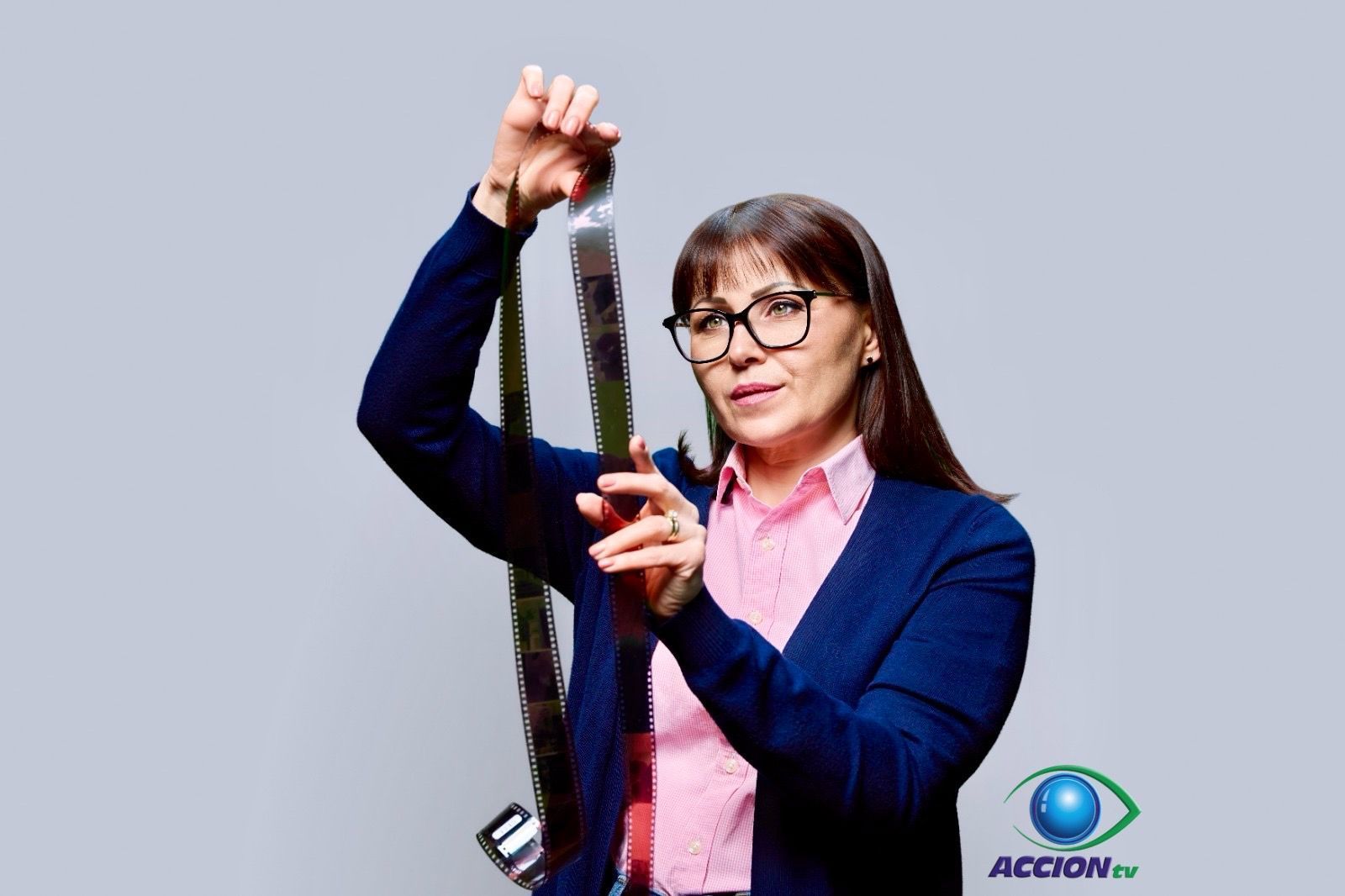Una mujer con un suéter azul sostiene un trozo de película.