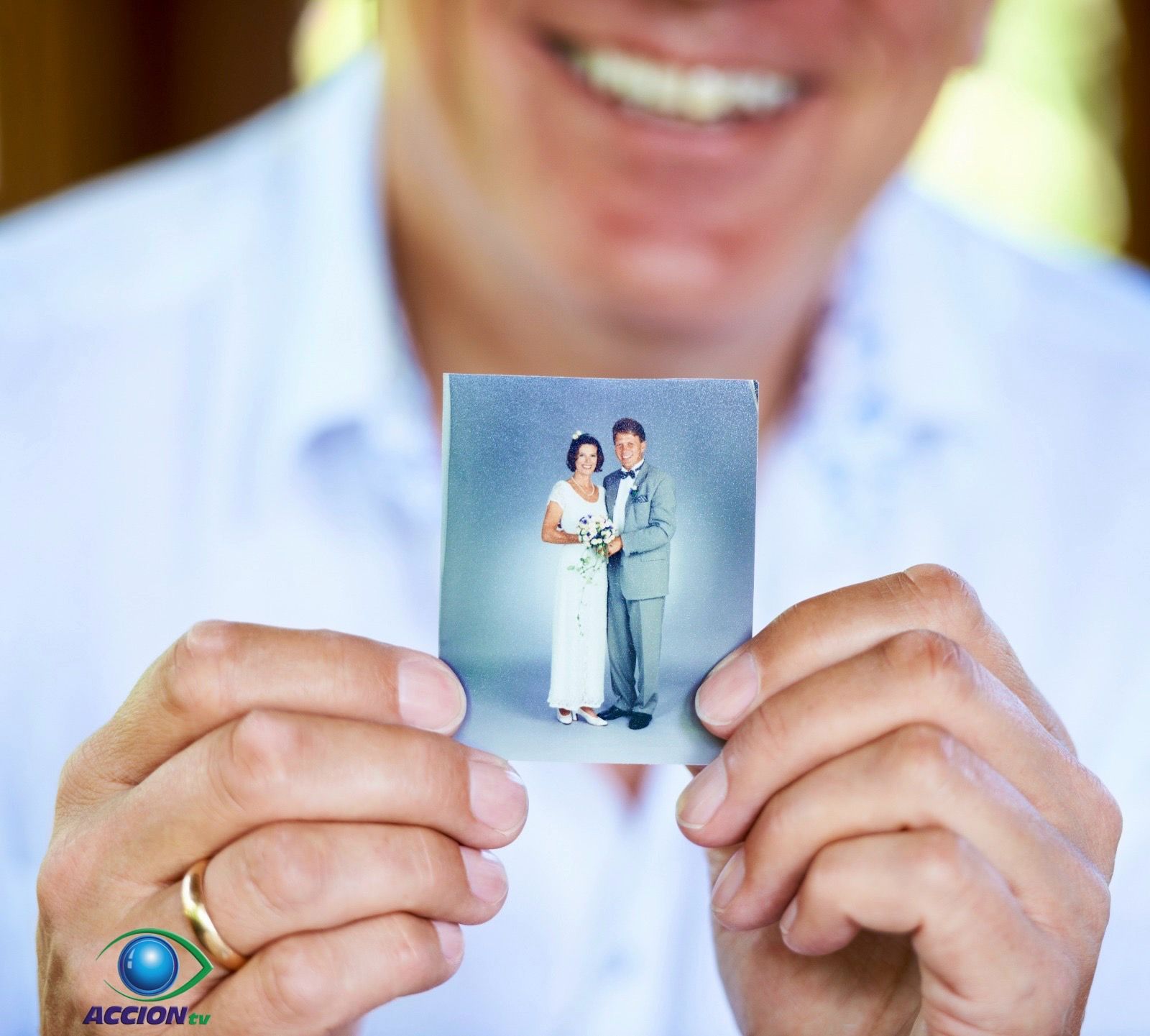 Un hombre sostiene una fotografía de una novia y un novio.
