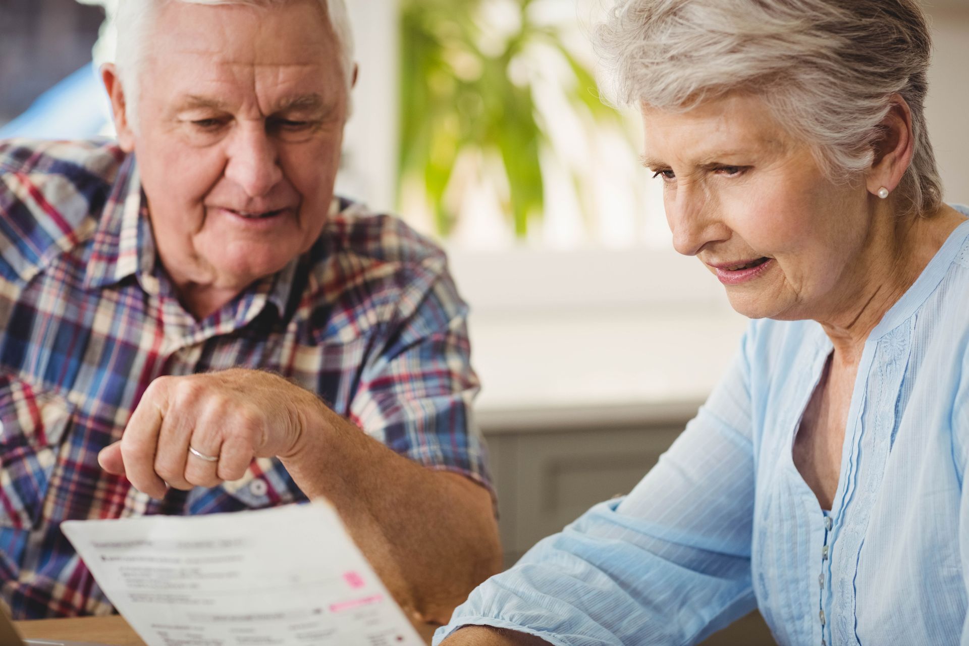 Two people reviewing papers together at a table in a bright home kitchen