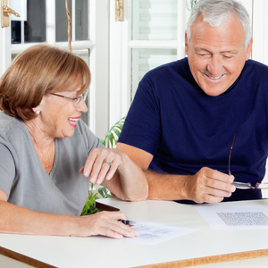 Two people smiling and reviewing papers at a table in a bright kitchen