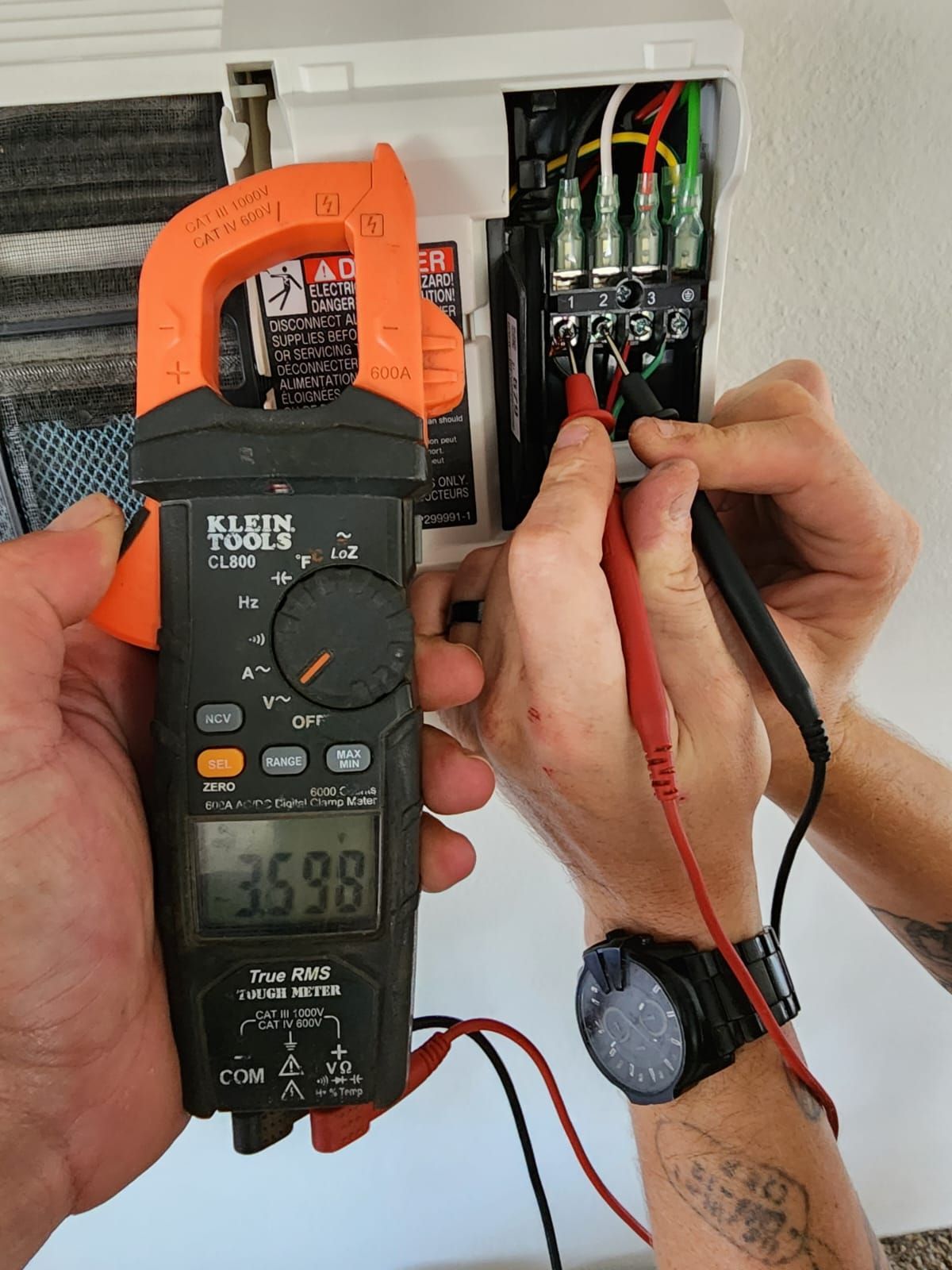 A man is using a kleins clamp meter to measure a current
