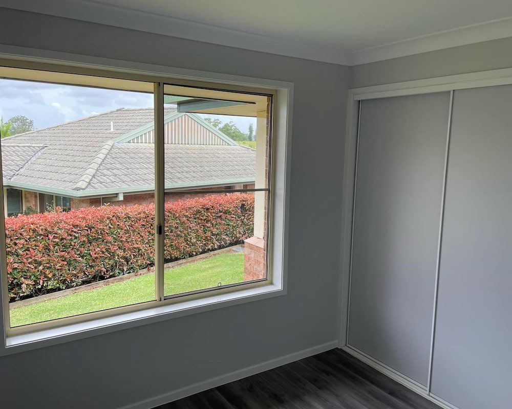 An Empty Room With a Large Window and Sliding Glass Doors — Cornall Painting Services in Wauchope, NSW 