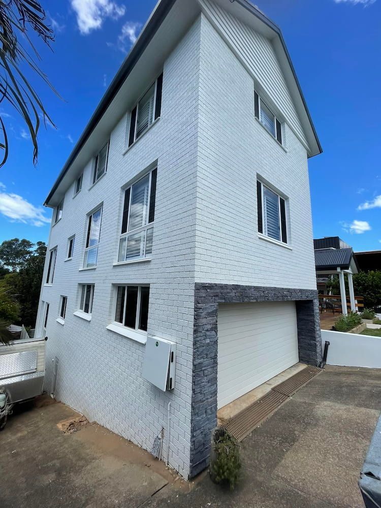 A Large White Brick Building With a Garage Underneath It — Cornall Painting Services in Wauchope, NSW 
