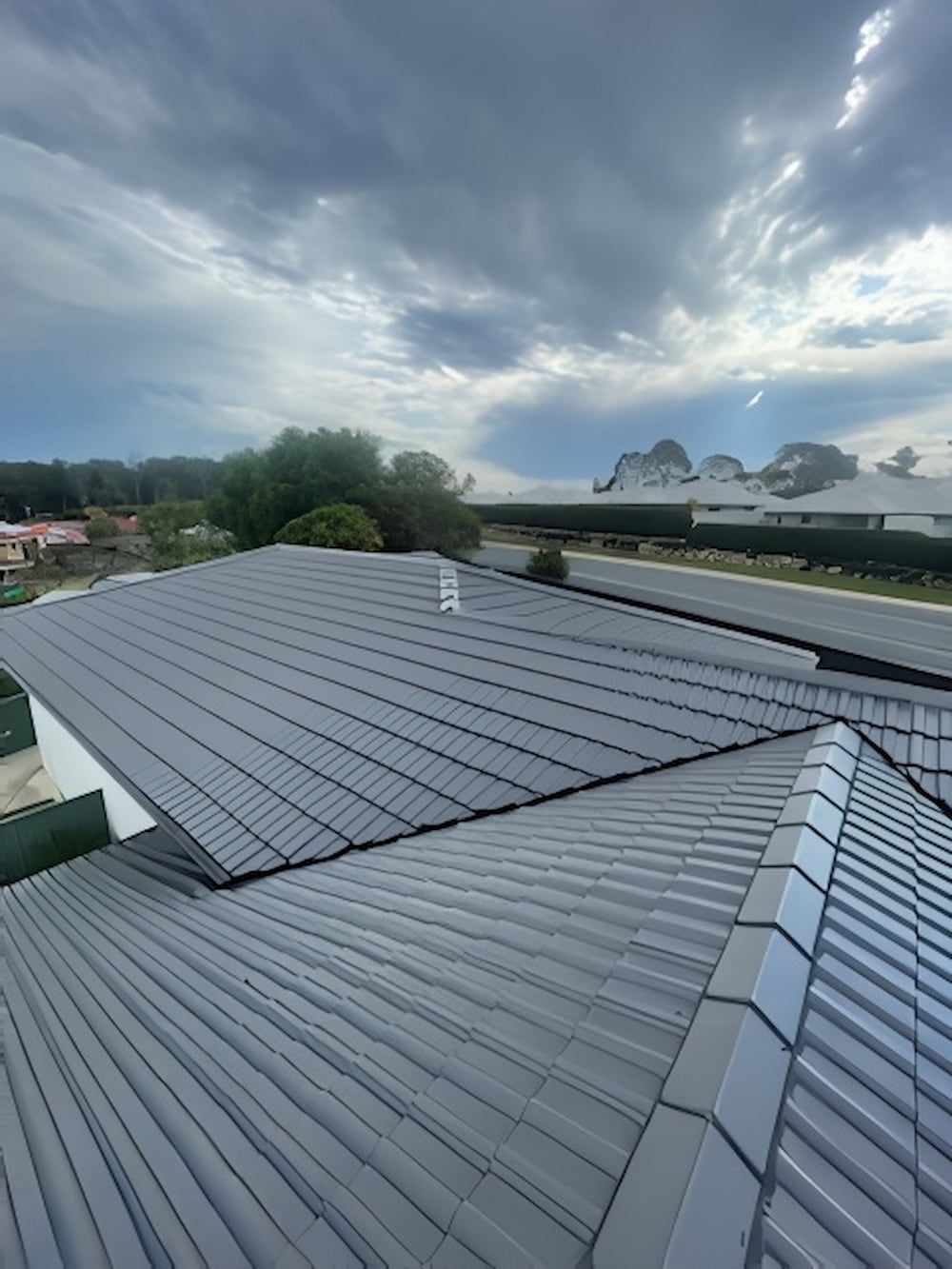 A Roof of a House With a Cloudy Sky in the Background — Cornall Painting Services in Port Macquarie, NSW 