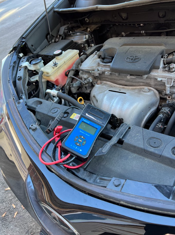 A car with the hood open and a device sitting on the engine.