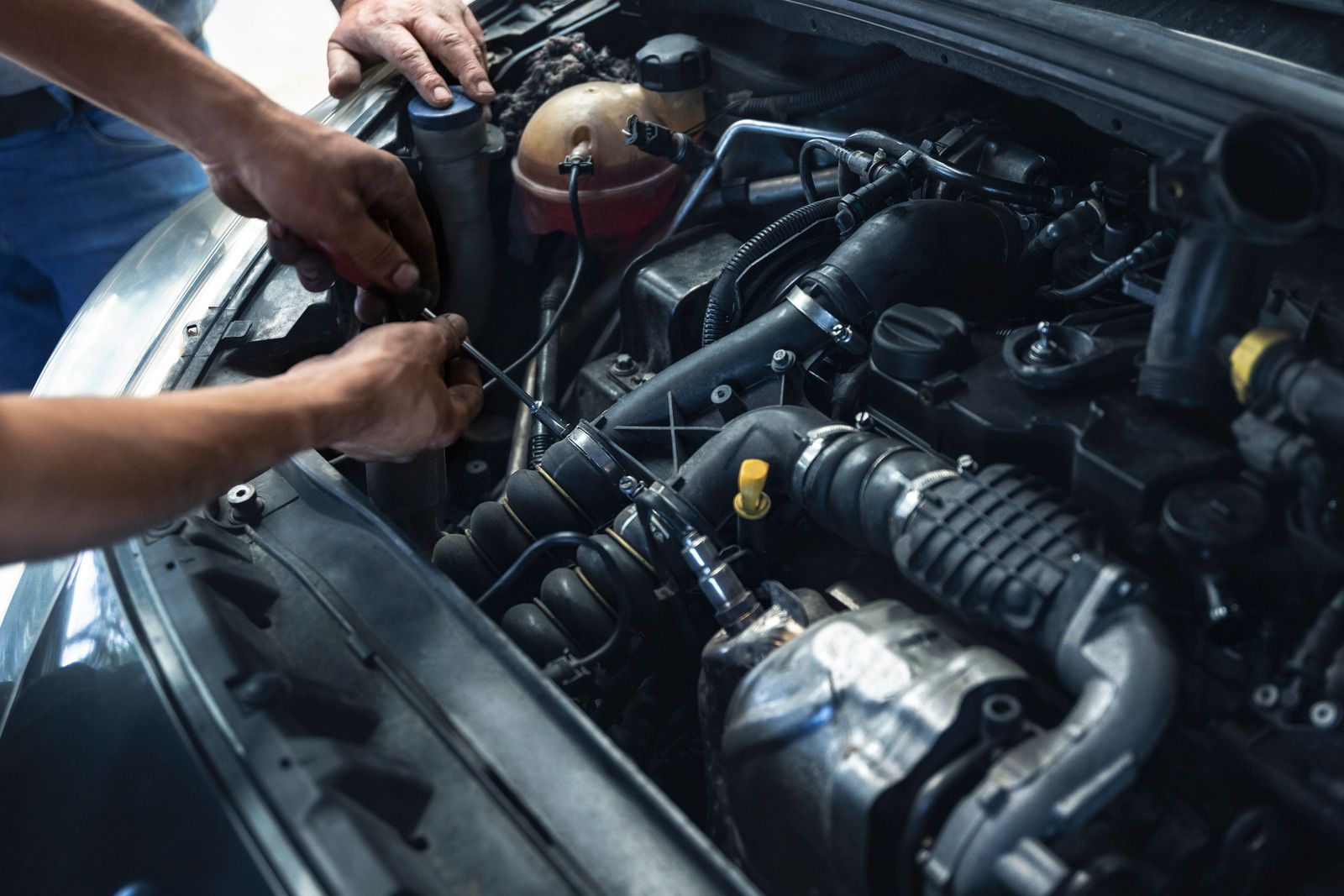 A man is working on the engine of a car.