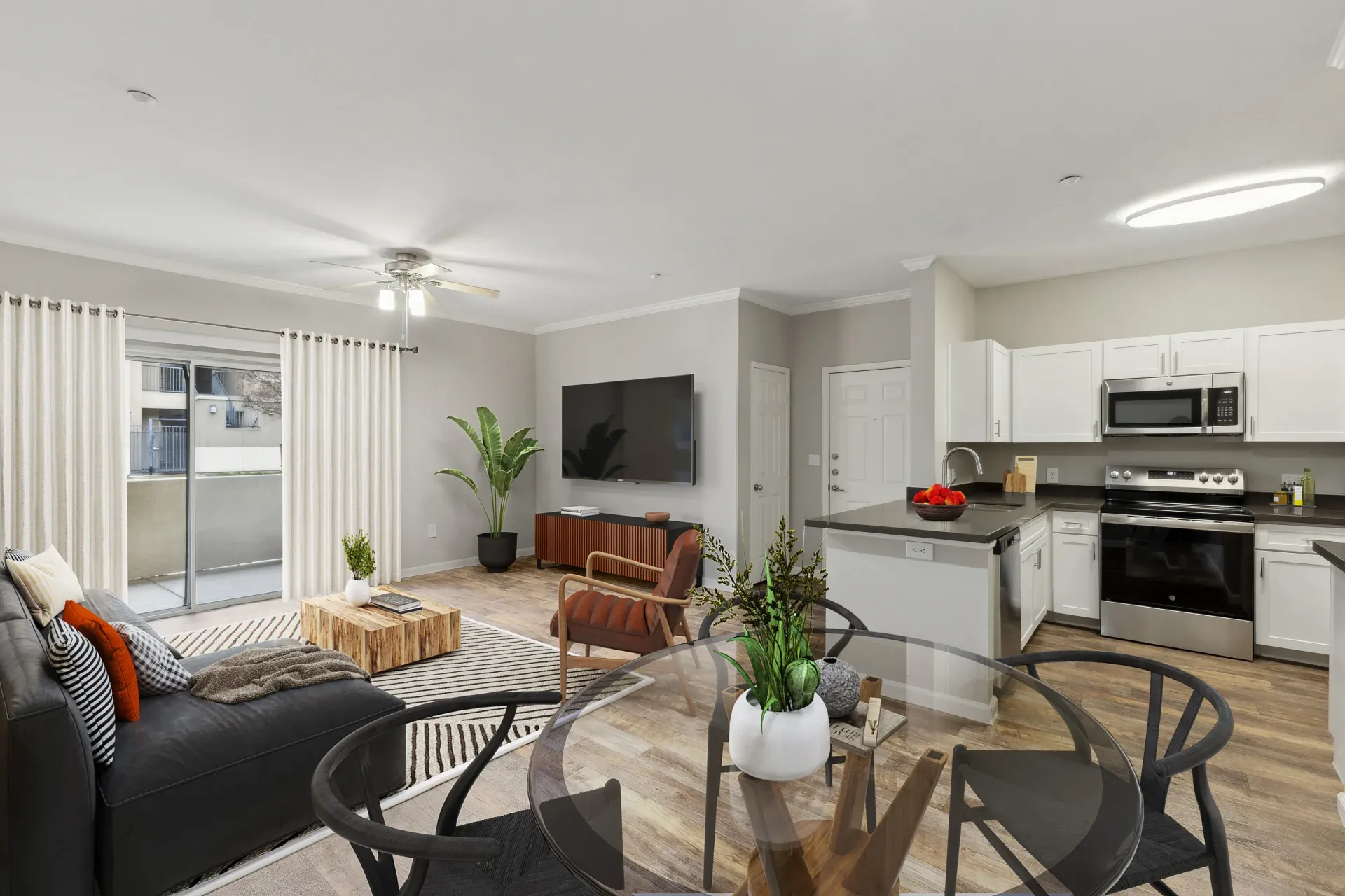 Open-concept living area with sofa, TV, dining table, and adjoining kitchen.