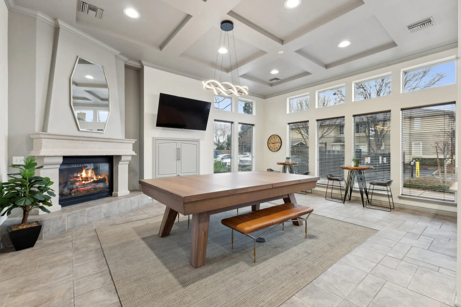 Community lounge with a lit fireplace, wall-mounted TV, and a pool table.