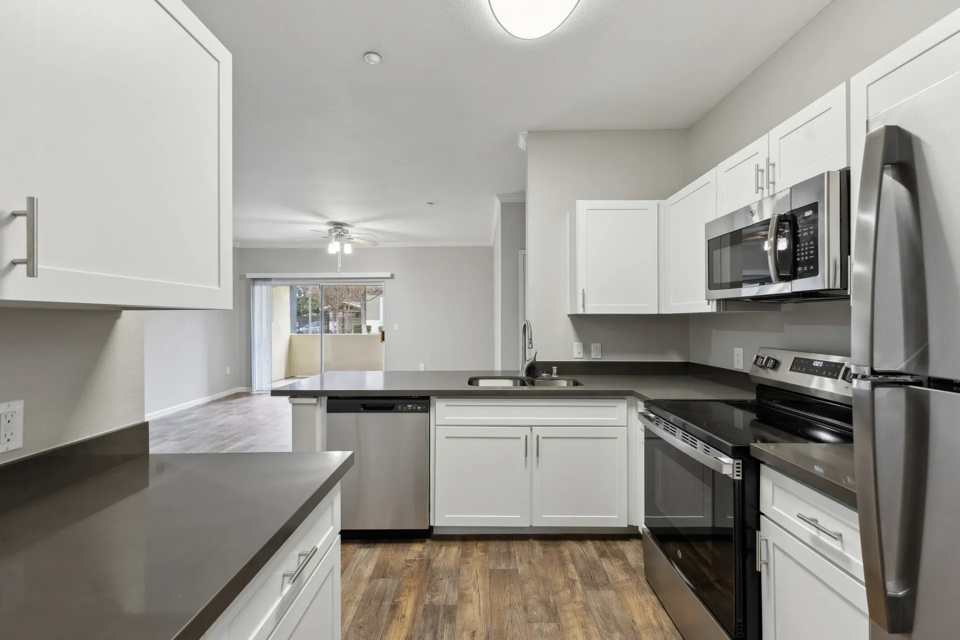 Bright kitchen with white cabinets, gray countertops, and stainless steel appliances.