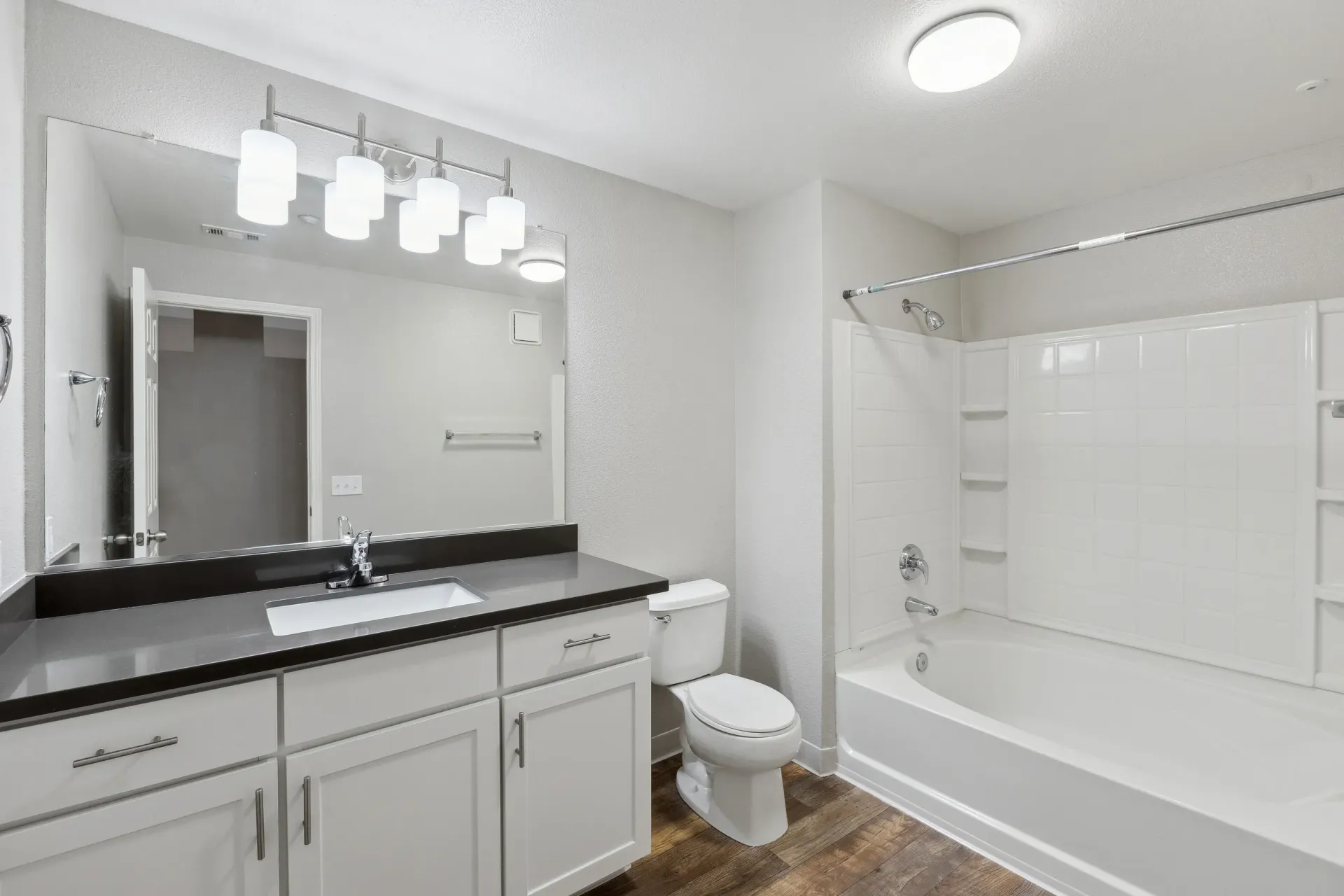Bathroom with white vanity, large mirror, toilet, and a tub/shower.