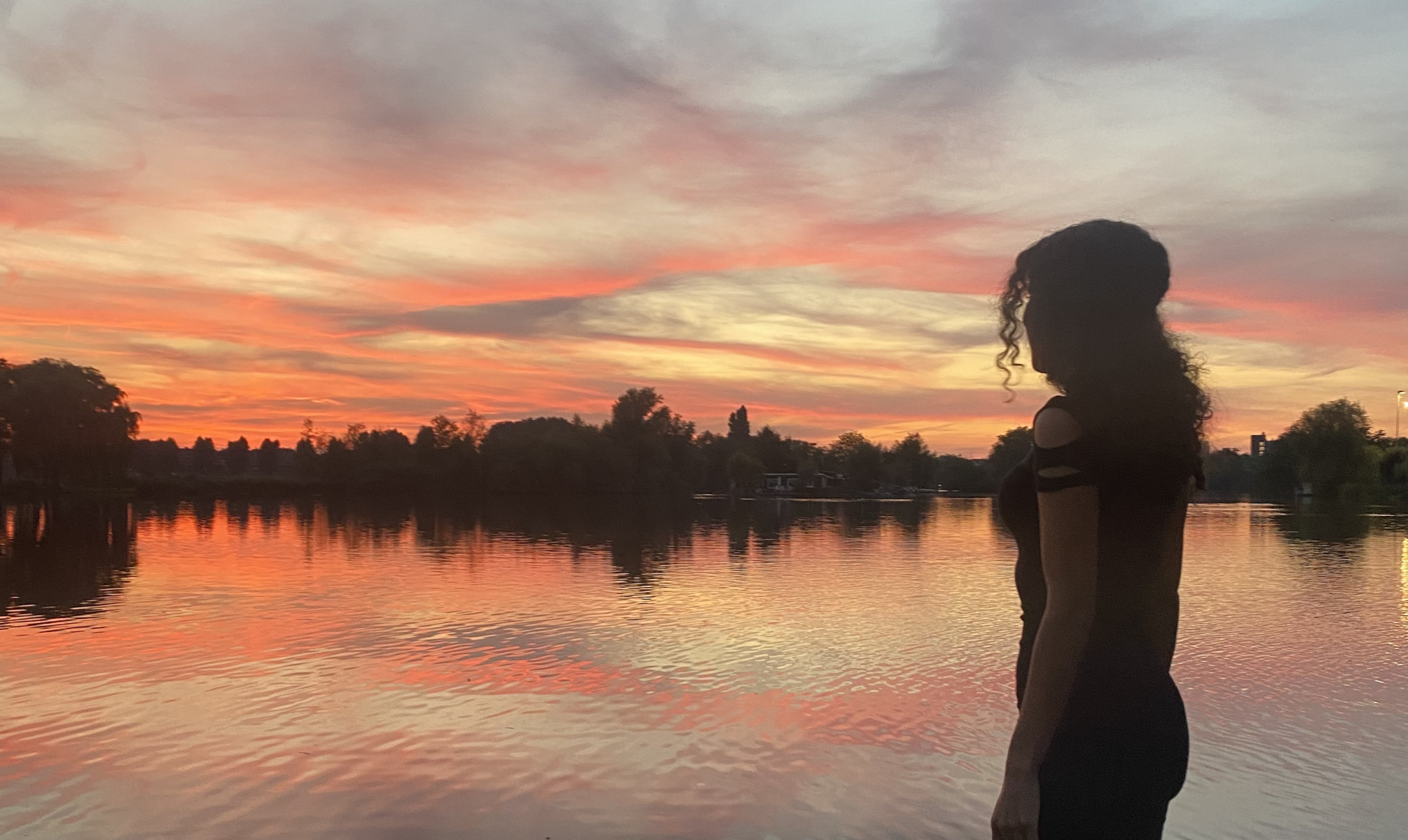 Vrouw silhouet voor water met zonsondergang