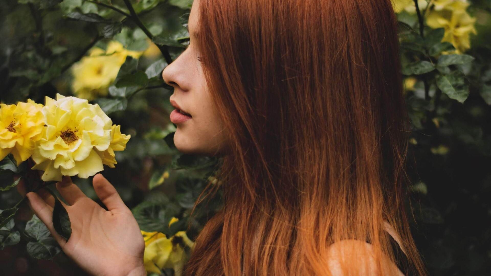 Vrouw ruikt aan bloem. Manifesteren hoef je niet te leren.