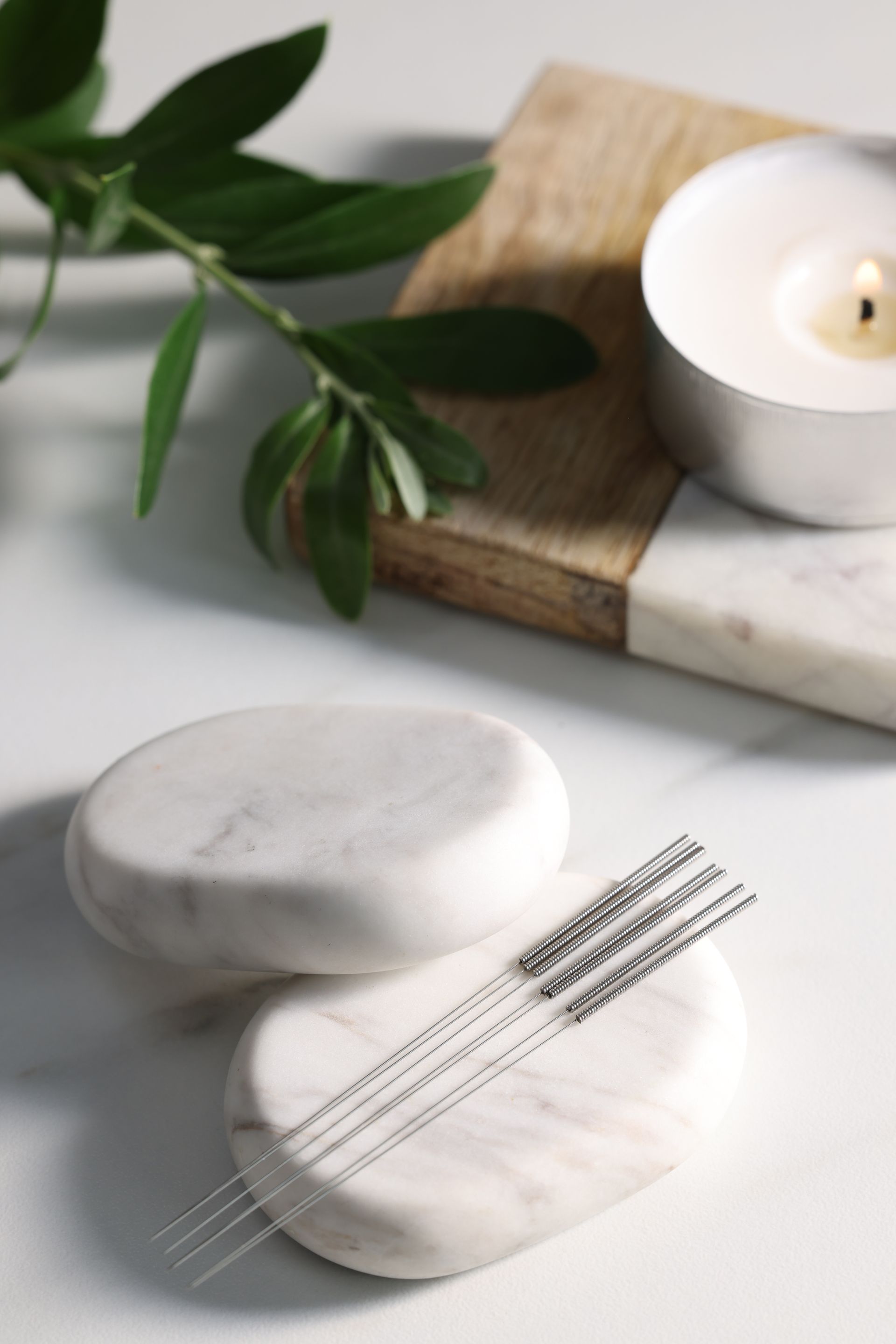 acupuncture needles sitting on marble blocks next to a candle