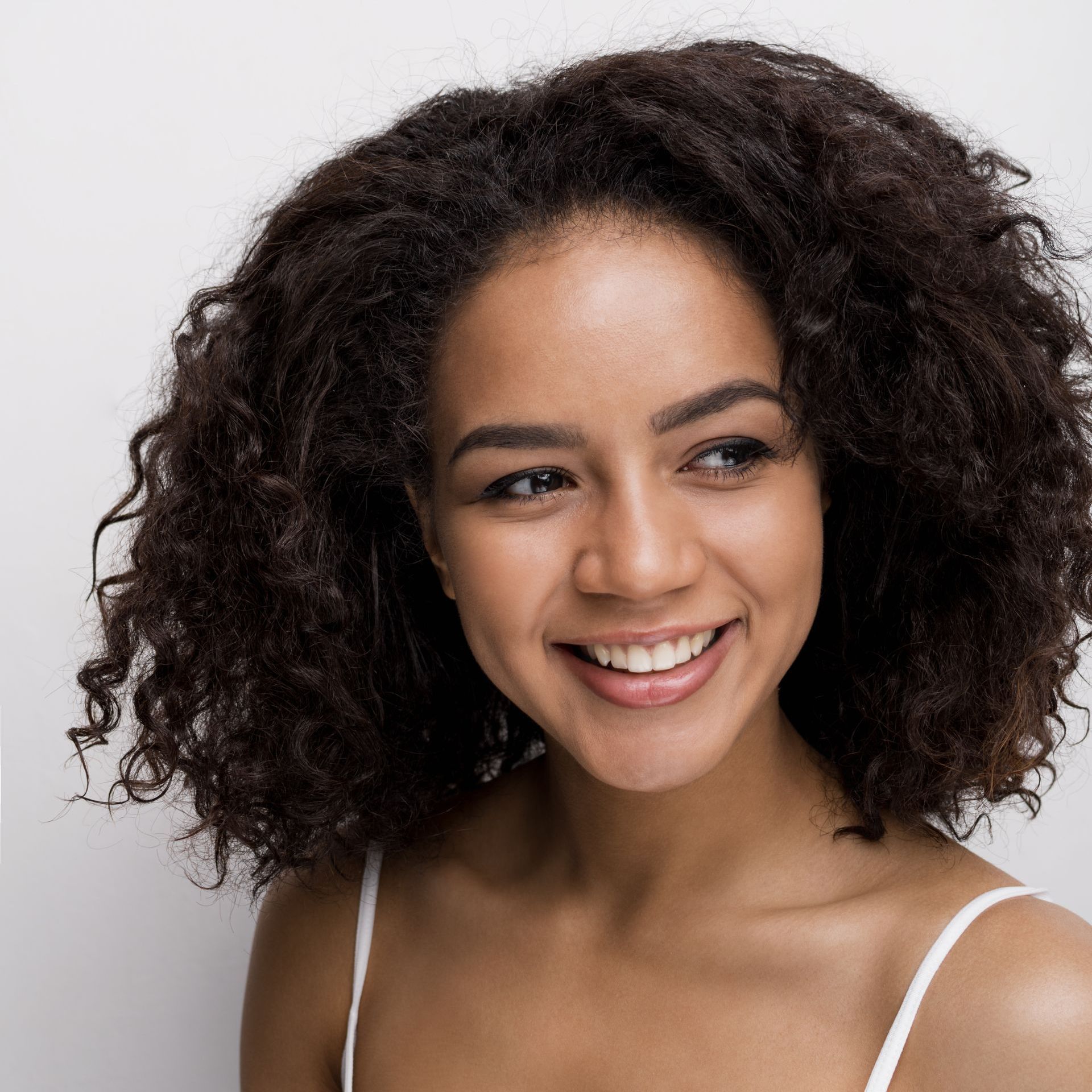 a woman with curly hair and hoop earrings is smiling .