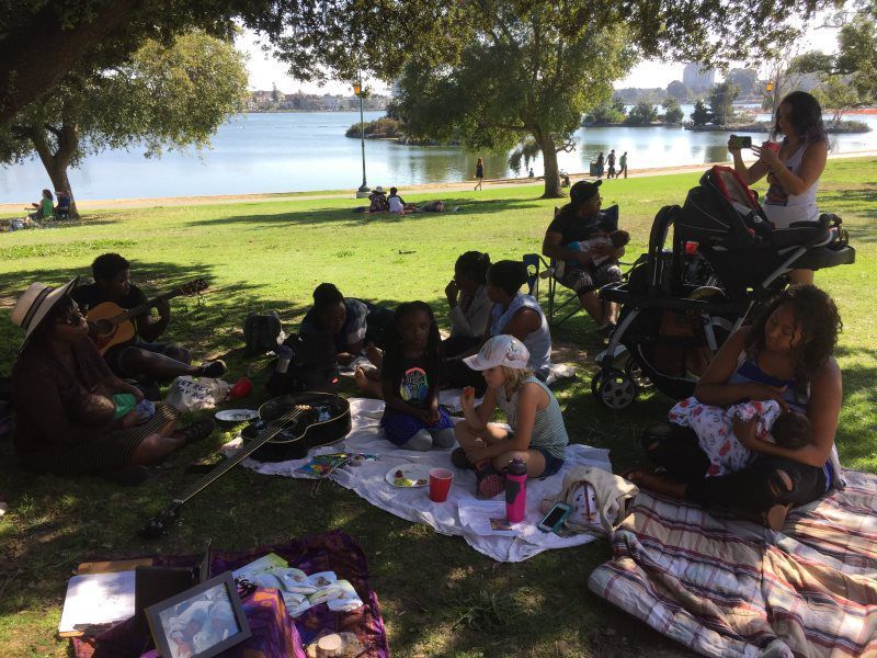 People picnicking and relaxing by a lake on a sunny day.