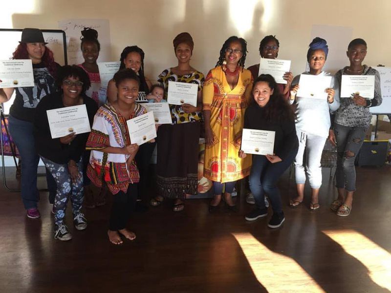 Group of people holding certificates, smiling for the camera in a room with natural light.