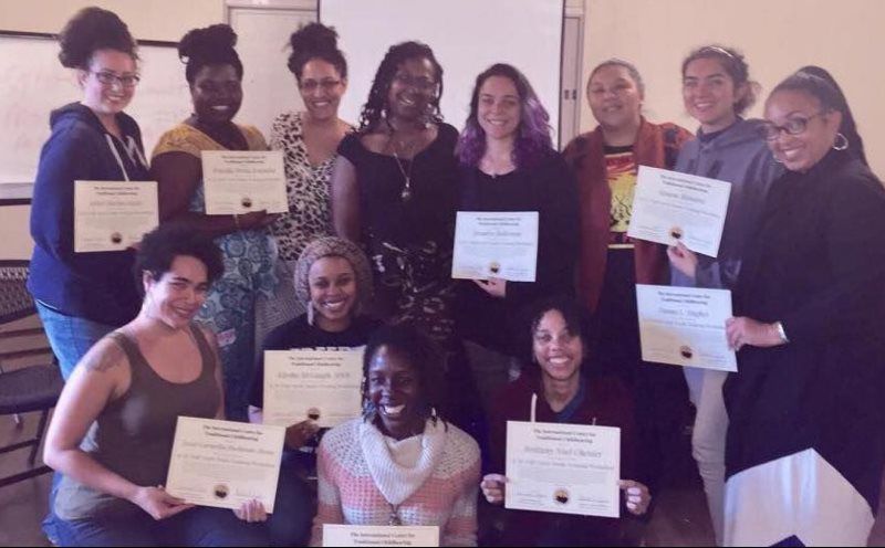 Group of women holding certificates, smiling, in a classroom setting.