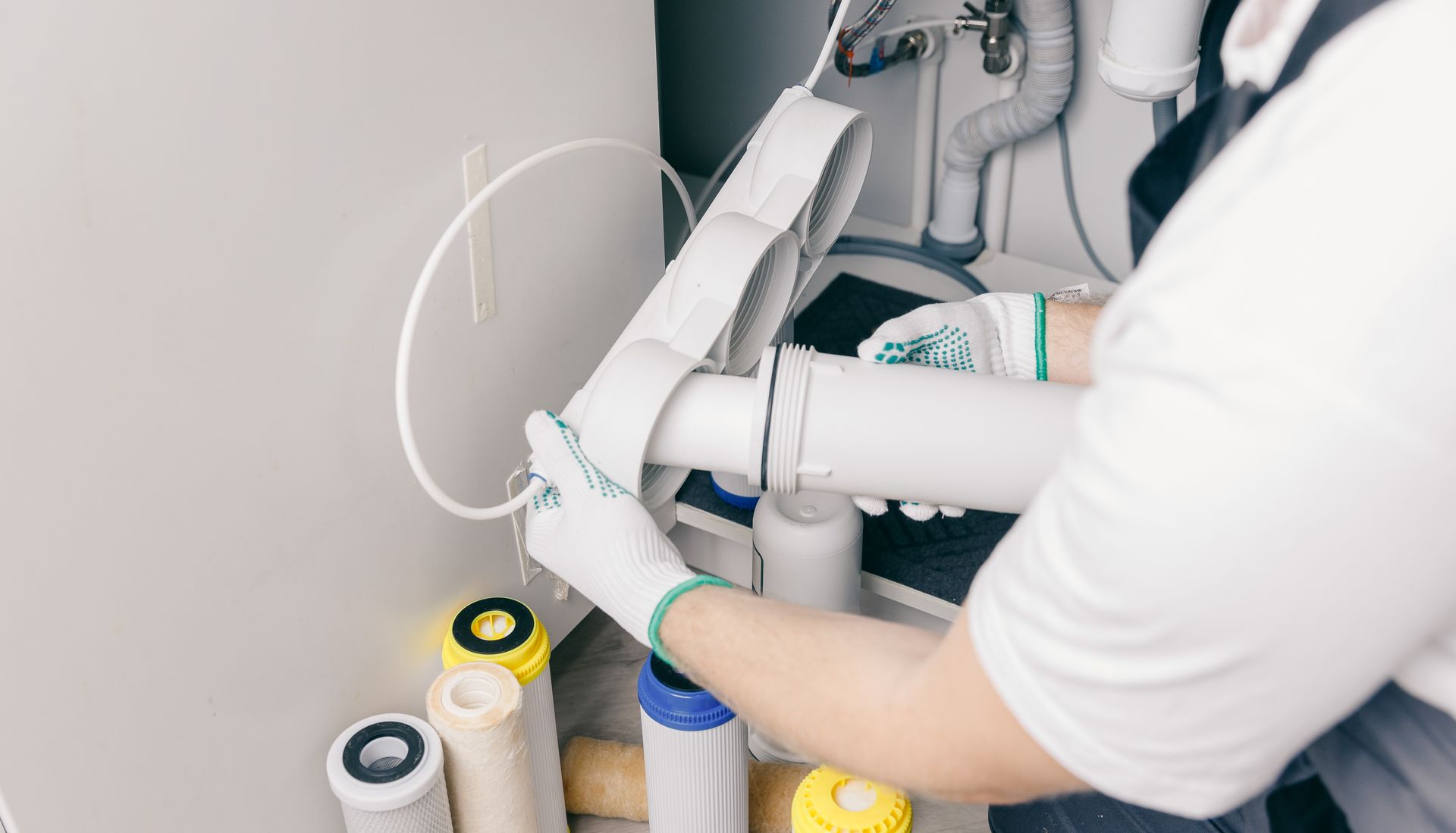 Person adjusting a white robotic arm in a workshop, with cables and parts on a workbench.